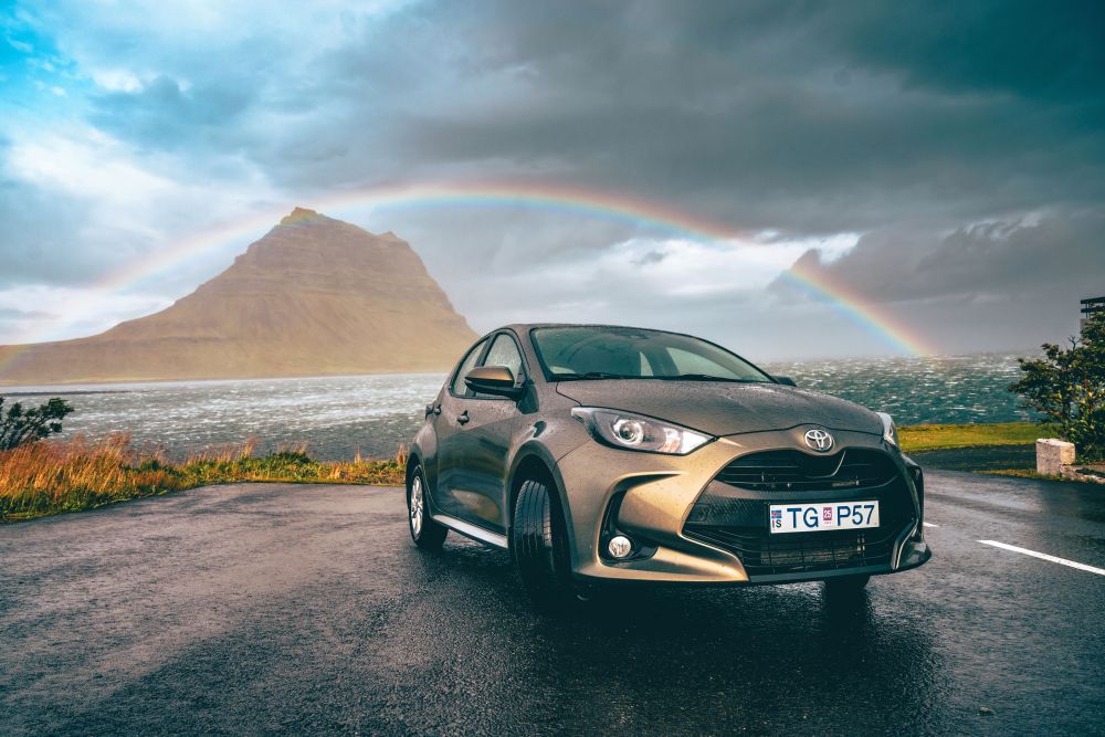 Toyota Yaris small car parked in front of Kirkjufell Mountain at Snæfellsnes Peninsula.