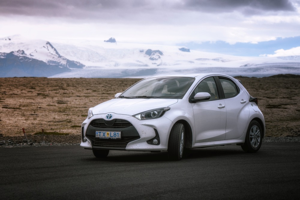 Economy car parked in front of a glacier in Iceland.