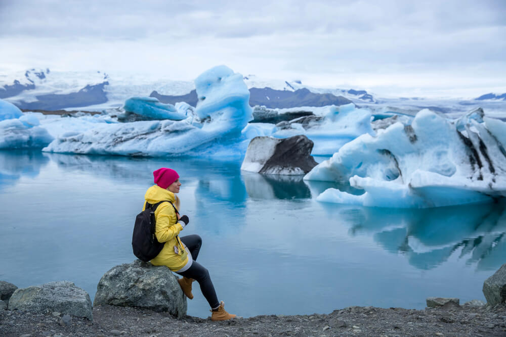 Woman sitting on a rock next to Jökulsárlón glacier lagoon in Iceland.