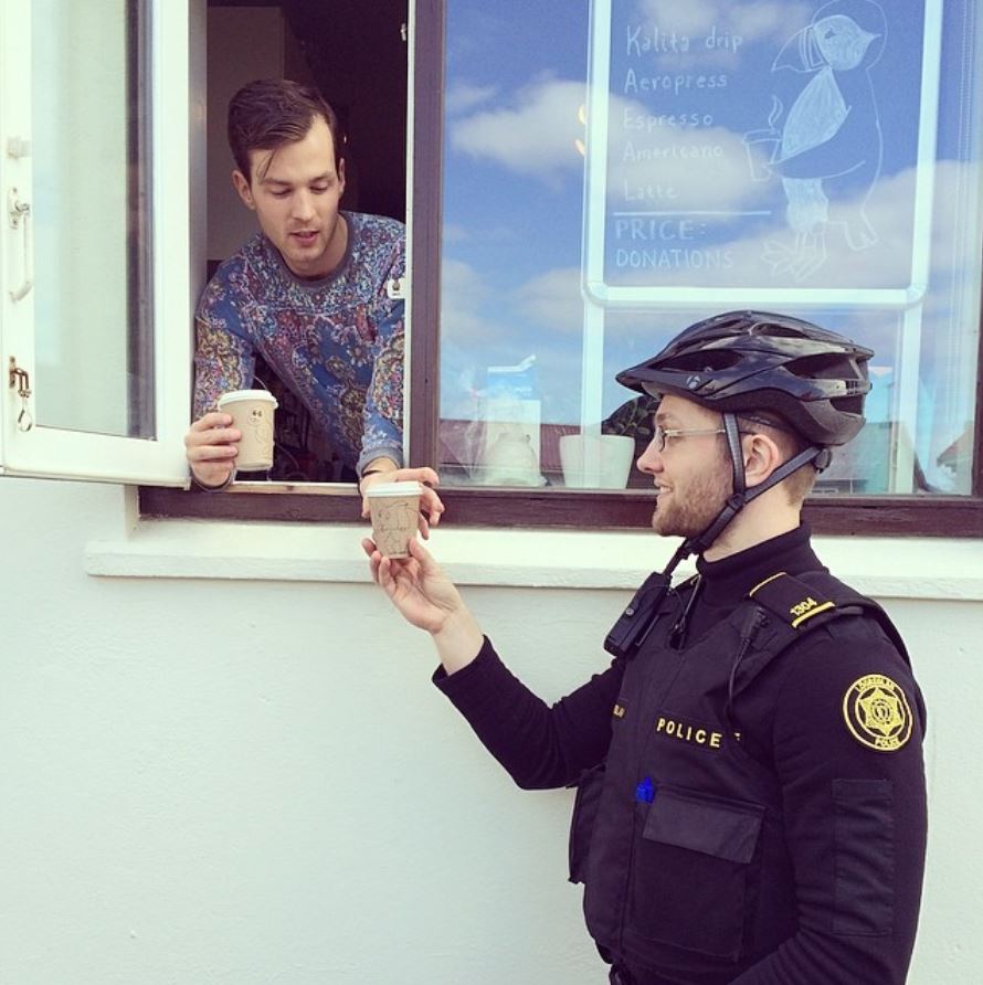 Police man getting coffee from a friendly person 