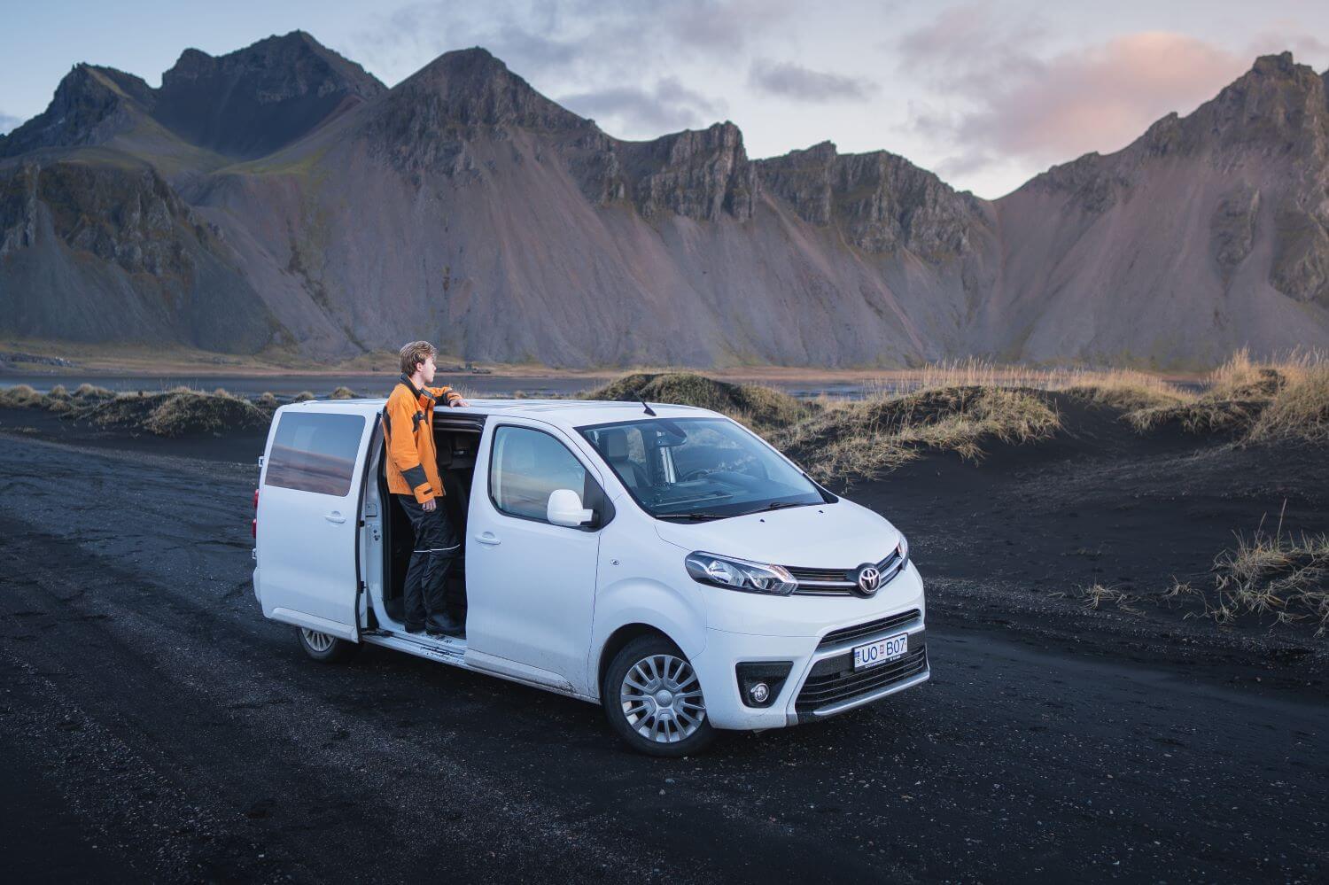 Men standing in the side door of a passenger van rental car.