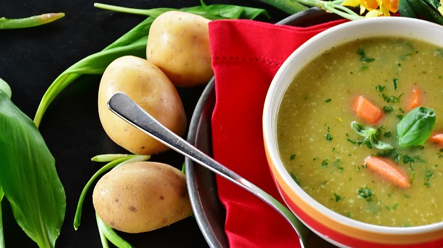 Bowl of potato soup with lettuce and potatos on a table