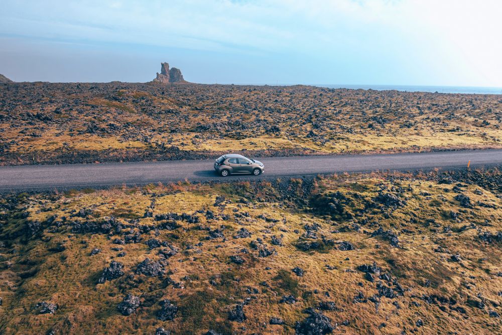 Car driving on a road through a lava field in Iceland.,