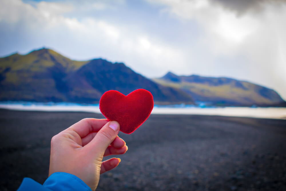 Iceland Valentine1 Person holding a red heart on Iceland black sand.